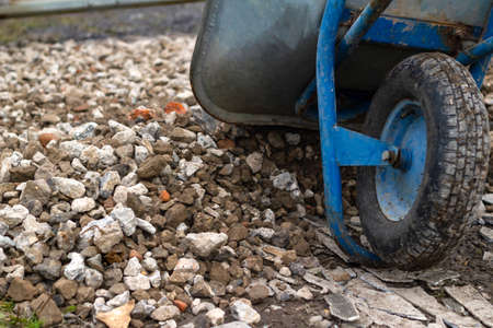 Trolley for building material. Distribution of rubble on the road. Concept: construction, road repairs, sale of crushed stone, backgrounds and textures, working tools.の写真素材