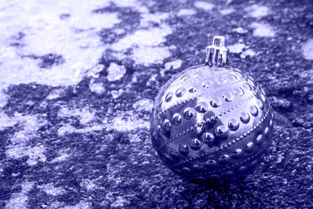 A shiny Christmas tree ball painted in the color of veri peri. Taken in close-up from the side on an icy surface. Concept: color of the year, Merry Christmas and New Year greetings.の写真素材