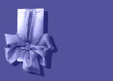 A shiny bow tying gift, painted in the color of the year veri peri. Close-up on the left. Space for text. Concept: trend of the year, Christmas and new year, mood board.の写真素材