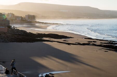 Woman taking a photo of Taghazout beachの写真素材