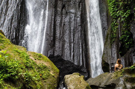 Woman meditating in front of dusun kuning waterfall, Bali, Indonesiaの写真素材