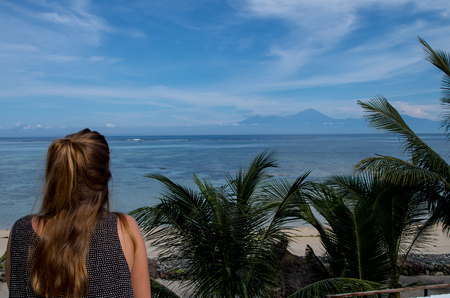 Woman looking towards Lombok from Sumbawa with copy space on the right.の写真素材