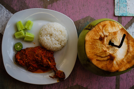 Typical Indonesian Dish: Nasi Ayam Plecing (Chicken with rice and special sauce) and young coconut birds eye.の写真素材