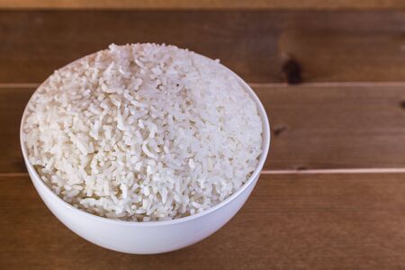 boiled rice in white bowl on the wooden background close upの写真素材