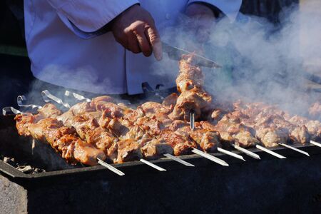 cooks barbecue meat on the street takes meat from skewers close-upの写真素材