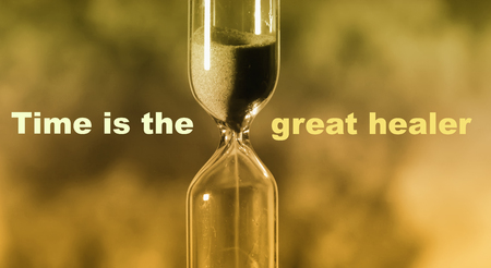 glass hourglass is pouring out the sand expires time. Time is the great healerの写真素材
