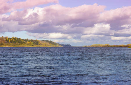 large beautiful cumulus clouds in the afternoon over a silver river in summerの写真素材