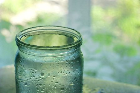 a water drop jar with water on the glass.  a can full of water by the window.の写真素材