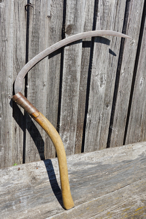rustic braid tool on the background of old gray boards. mow grass.の写真素材