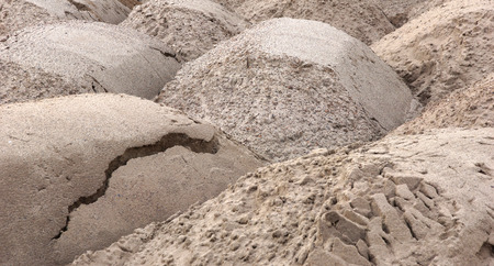 the sand lies in heaps brought by truck to the building construction start