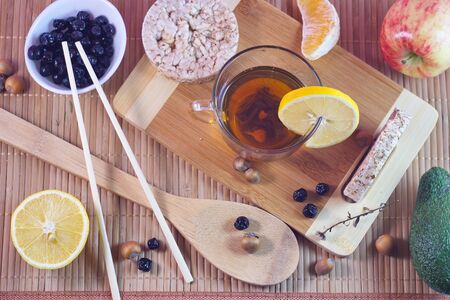 Flatley concept healthy food Jasmine Chinese tea in a Cup five grain loaves avocado apples chokeberry lemon and orange slices nuts on a wooden bamboo background close-upの写真素材