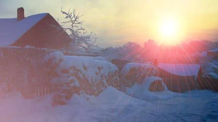 winter landscape village snow sunset red sun.snow-covered wooden houses firewood under the snow....