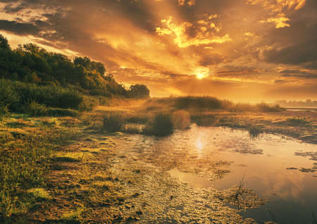 beautiful summer landscape of the morning sun over the river lake dramatic sky