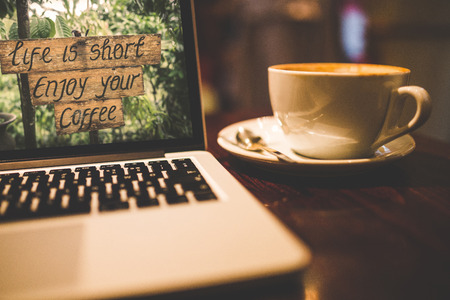 Life is short enjoy your coffee text on laptop screen with cup of coffee