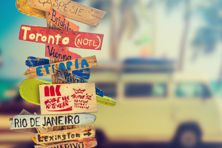 Retro wooden signpost to holiday destination near beach, mini colorful van background. Travel and holiday concept.の写真素材