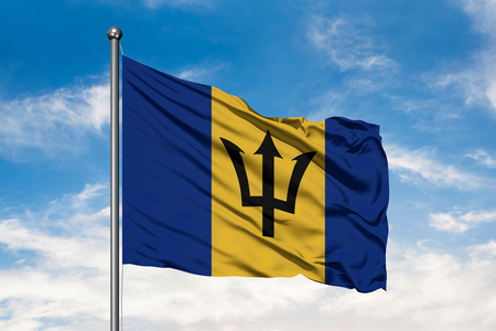 Flag of Barbados waving in the wind against white cloudy blue sky. Barbadian flag.の写真素材