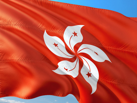 Flag of Honk Kong waving in the wind against deep blue sky. High quality fabric.の写真素材