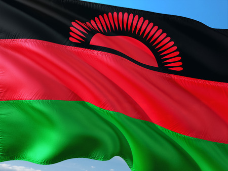Flag of Malawi waving in the wind against deep blue sky. High quality fabric.の写真素材