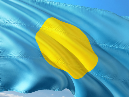 Flag of Palau waving in the wind against deep blue sky. High quality fabric.の写真素材