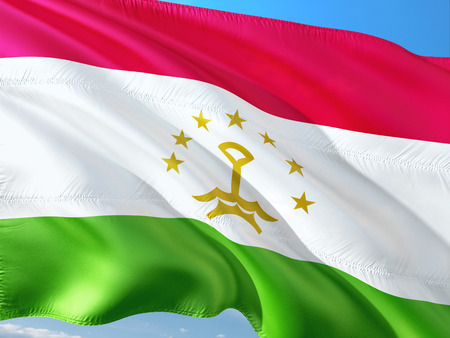 Flag of Tajikistan waving in the wind against deep blue sky. High quality fabric.の写真素材
