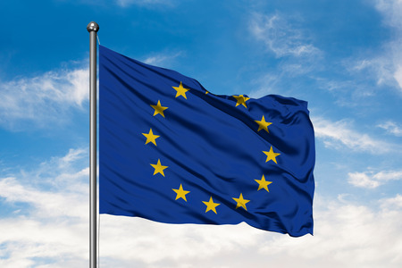 Flag of European Union waving in the wind against white cloudy blue sky.の写真素材