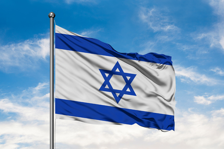 Flag of Israel waving in the wind against white cloudy blue sky. Israeli flag.の写真素材