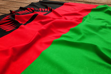 Flag of Malawi on a wooden desk background. Silk Malawian flag top view.の写真素材