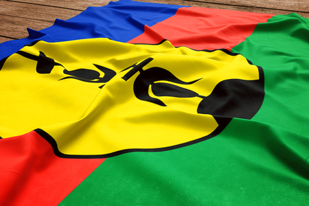Flag of New Caledonia on a wooden desk background. Silk flag top view.の写真素材