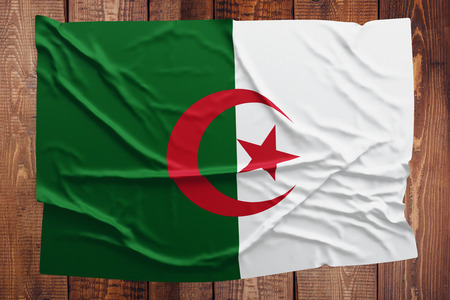 Flag of Algeria on a wooden table background. Wrinkled Algerian flag top view.の写真素材