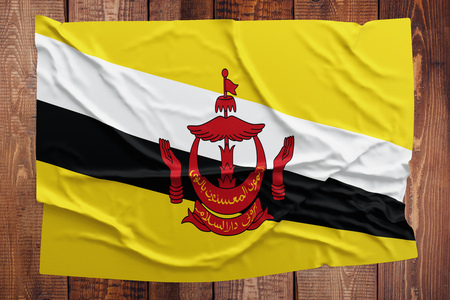 Flag of Brunei on a wooden table background. Wrinkled Bruneian flag top view.の写真素材