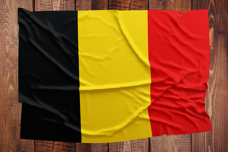 Flag of Belgium on a wooden table background. Wrinkled Belgian flag top view.の写真素材