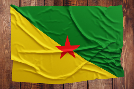 Flag of French Guiana on a wooden table background. Wrinkled Guiana flag top view.の写真素材