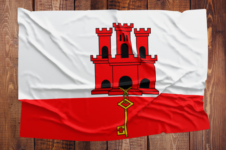 Flag of Gibraltar on a wooden table background. Wrinkled flag top view.の写真素材