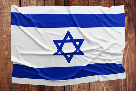 Flag of Israel on a wooden table background. Wrinkled Israeli flag top view.