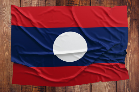 Flag of Laos on a wooden table background. Wrinkled Laotian flag top view.の写真素材
