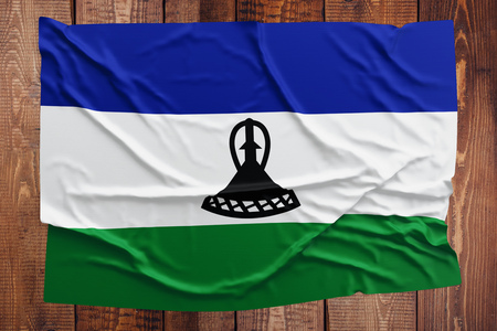Flag of Lesotho on a wooden table background. Wrinkled Mosotho flag top view.の写真素材