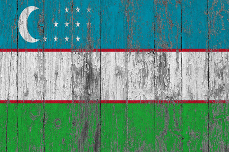 Flag of Uzbekistan painted on worn out wooden texture background.の写真素材
