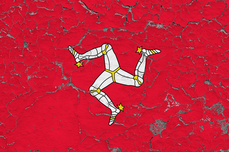 Flag of Isle Of Man painted on cracked dirty wall. National pattern on vintage style surface.の写真素材