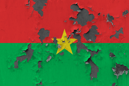 Close up grungy, damaged and weathered Burkina Faso flag on wall peeling off paint to see inside surface.の写真素材