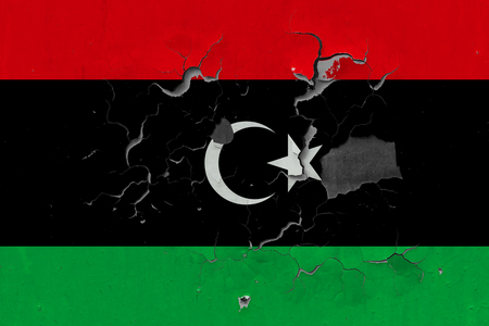 Close up grungy, damaged and weathered Libya flag on wall peeling off paint to see inside surface.の写真素材