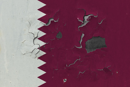 Close up grungy, damaged and weathered Qatar flag on wall peeling off paint to see inside surface.の写真素材