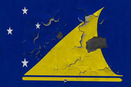 Close up grungy, damaged and weathered Tokelau flag on wall peeling off paint to see inside surface.の写真素材
