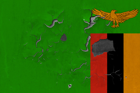 Close up grungy, damaged and weathered Zambia flag on wall peeling off paint to see inside surface.の写真素材