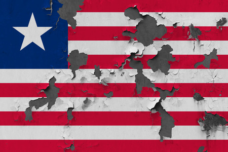 Close up grungy, damaged and weathered Liberia flag on wall peeling off paint to see inside surface.の写真素材