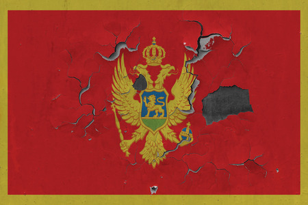 Close up grungy, damaged and weathered Montenegro flag on wall peeling off paint to see inside surface.の写真素材