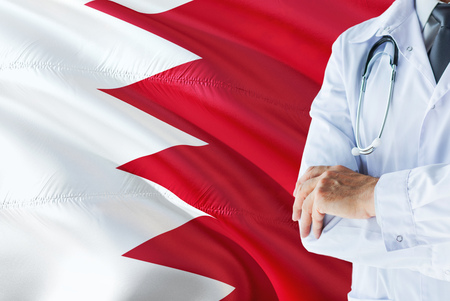 Bahraini Doctor standing with stethoscope on Bahrain flag background. National healthcare system concept, medical theme.の写真素材