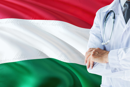 Hungarian Doctor standing with stethoscope on Hungary flag background. National healthcare system concept, medical theme.の写真素材