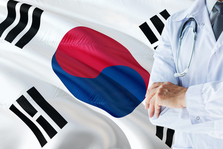 South Korean Doctor standing with stethoscope on South Korea flag background. National healthcare system concept, medical theme.の写真素材