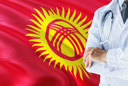 Kyrgyz Doctor standing with stethoscope on Kyrgyzstan flag background. National healthcare system concept, medical theme.の写真素材