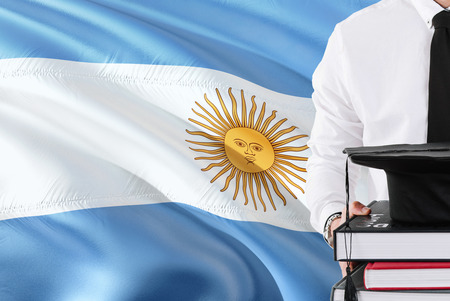 Successful Argentine student education concept. Holding books and graduation cap over Argentina flag background.の写真素材